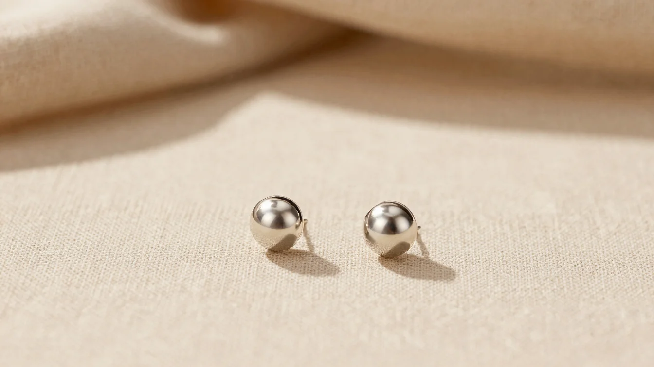 Warm editorial studio photography of elegant small steel earrings