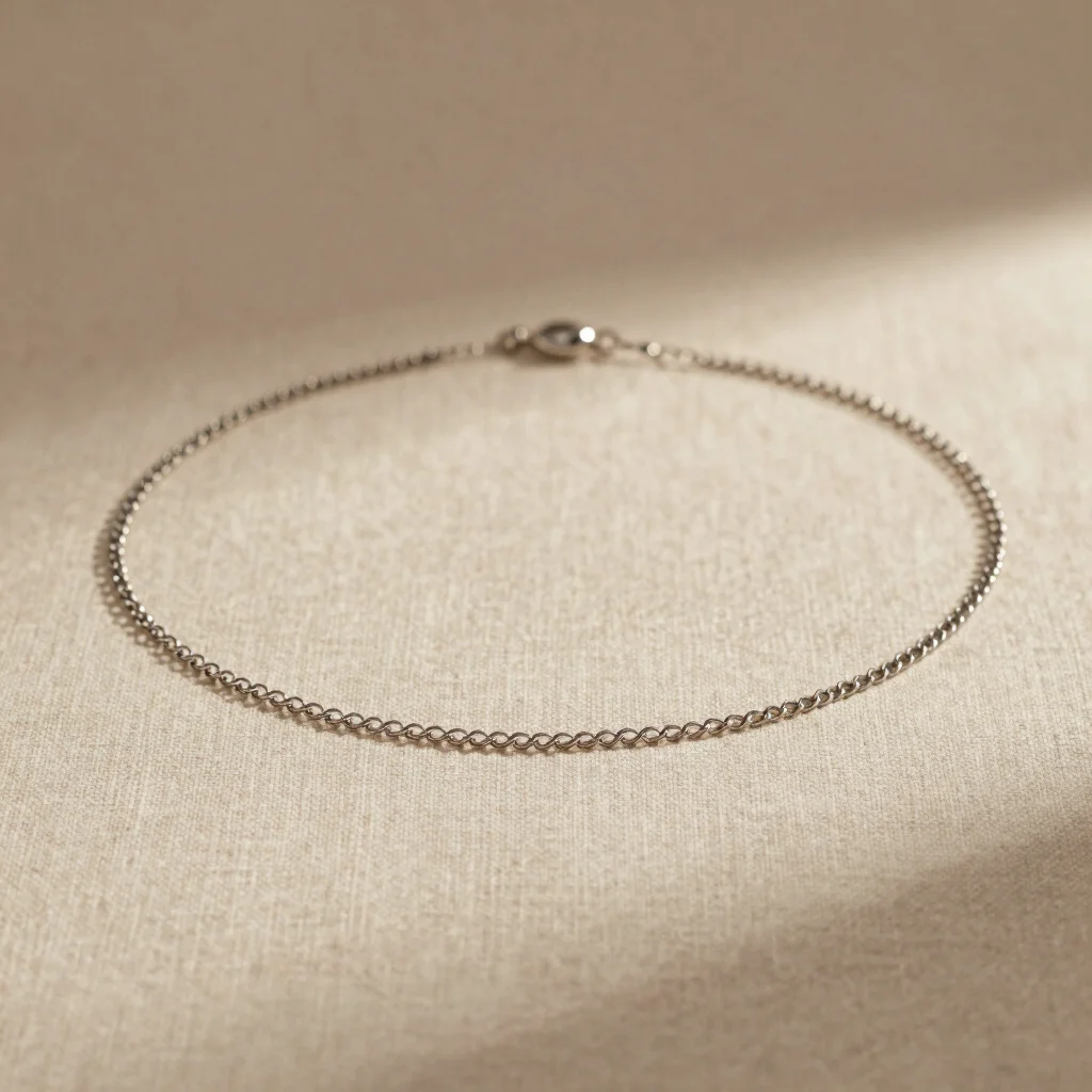 close-up of a subtle stainless steel choker chain on natural beige linen, warm and soft lighting, refined aesthetic