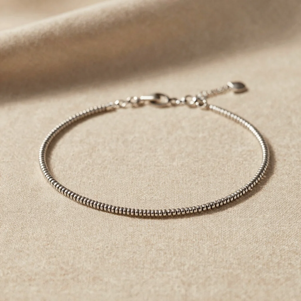 warm editorial studio photography of a fine stainless steel necklace resting on natural beige linen, soft daylight, shal